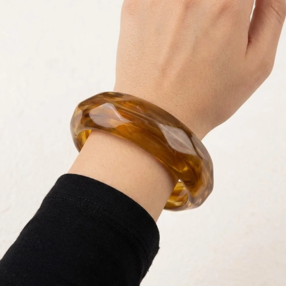 دستبند زنانه بنگل رزینی مدل اَمبریا کهربایی موج‌دار