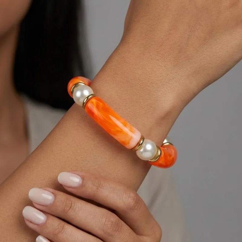 دستبند زنانه بنگل رزینی و مرواریدی چندتکه مدل پِرلورا نارنجی‑طلایی